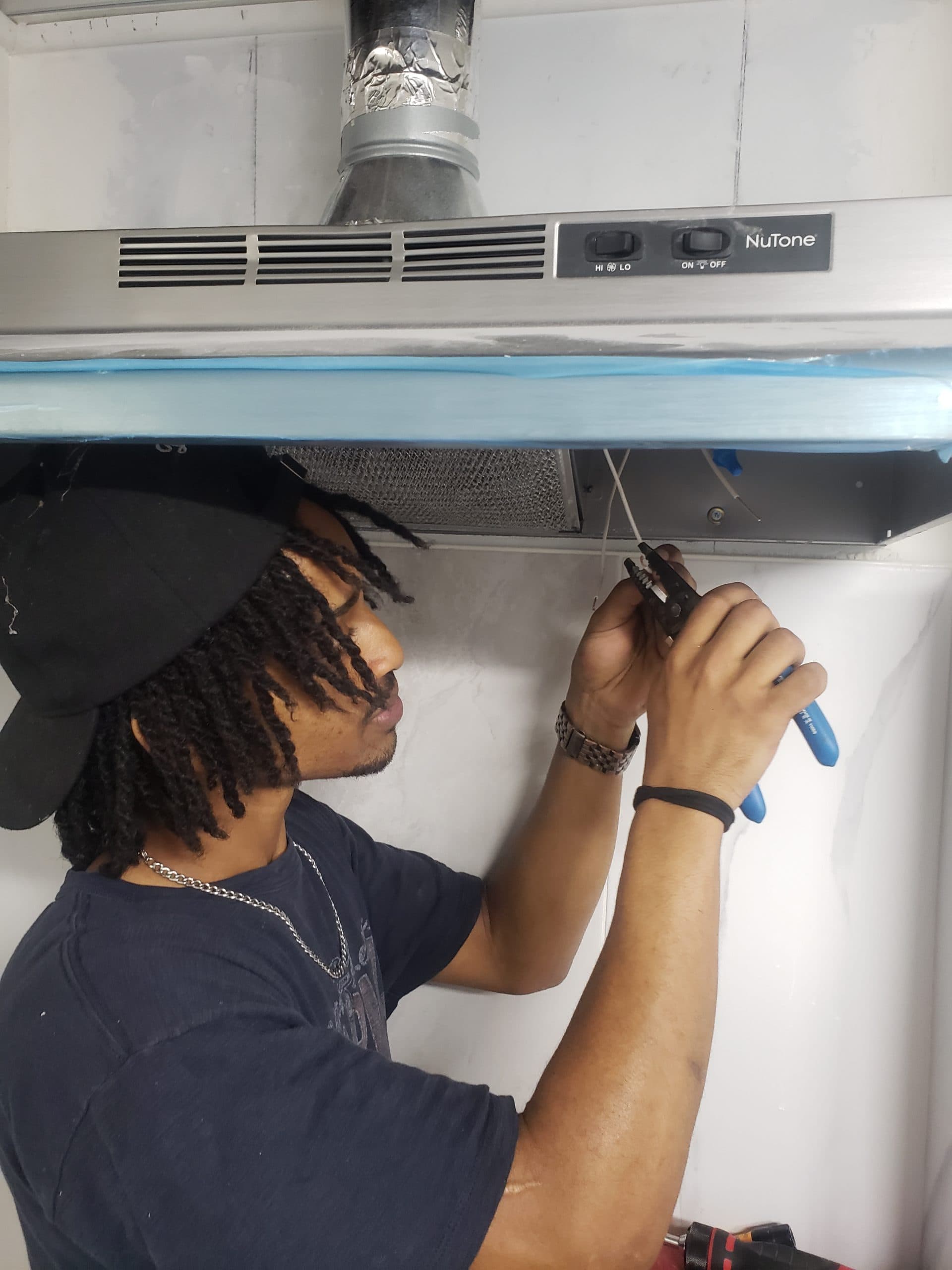 A Big Red Builds crew member installing a range hood