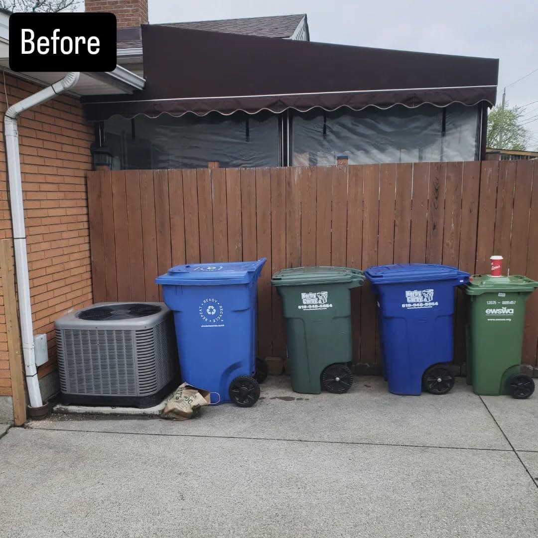 Exposed AC unit and garbage bins before the enclosure