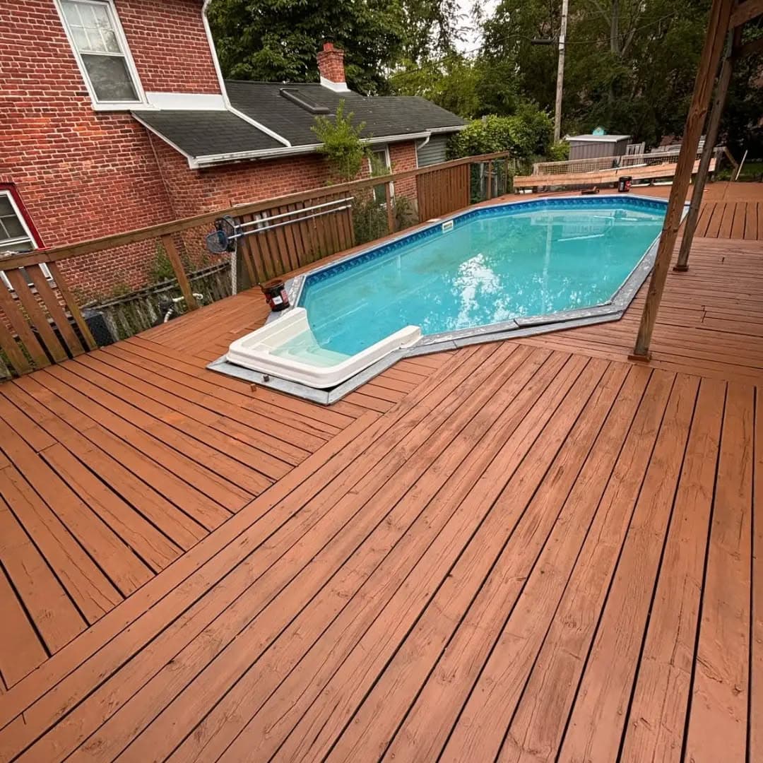 Restored pool deck with a fresh red-brown protective coating beside the pool